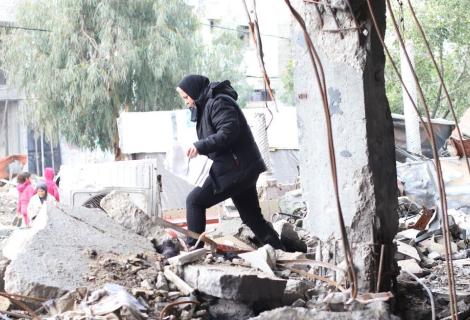 A lady walking through rumble of destroyed building in Gaza